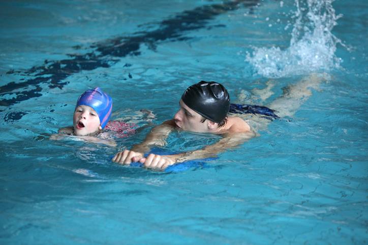Father teaching son to swim in pool