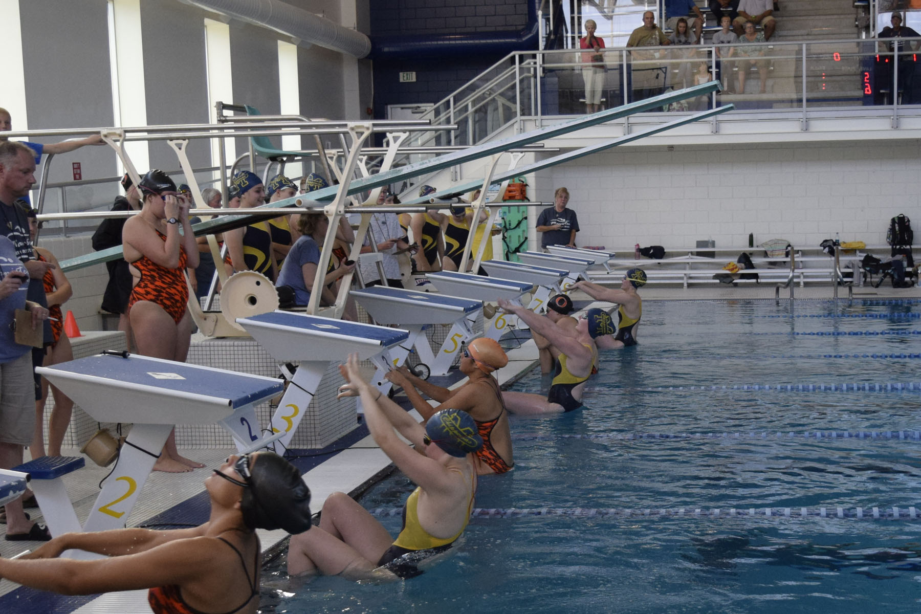 Manistee Chippewas Girls Swimming Team in Pool at competition meet on starting blocks