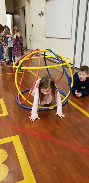 Student crawls through hula hoop ball