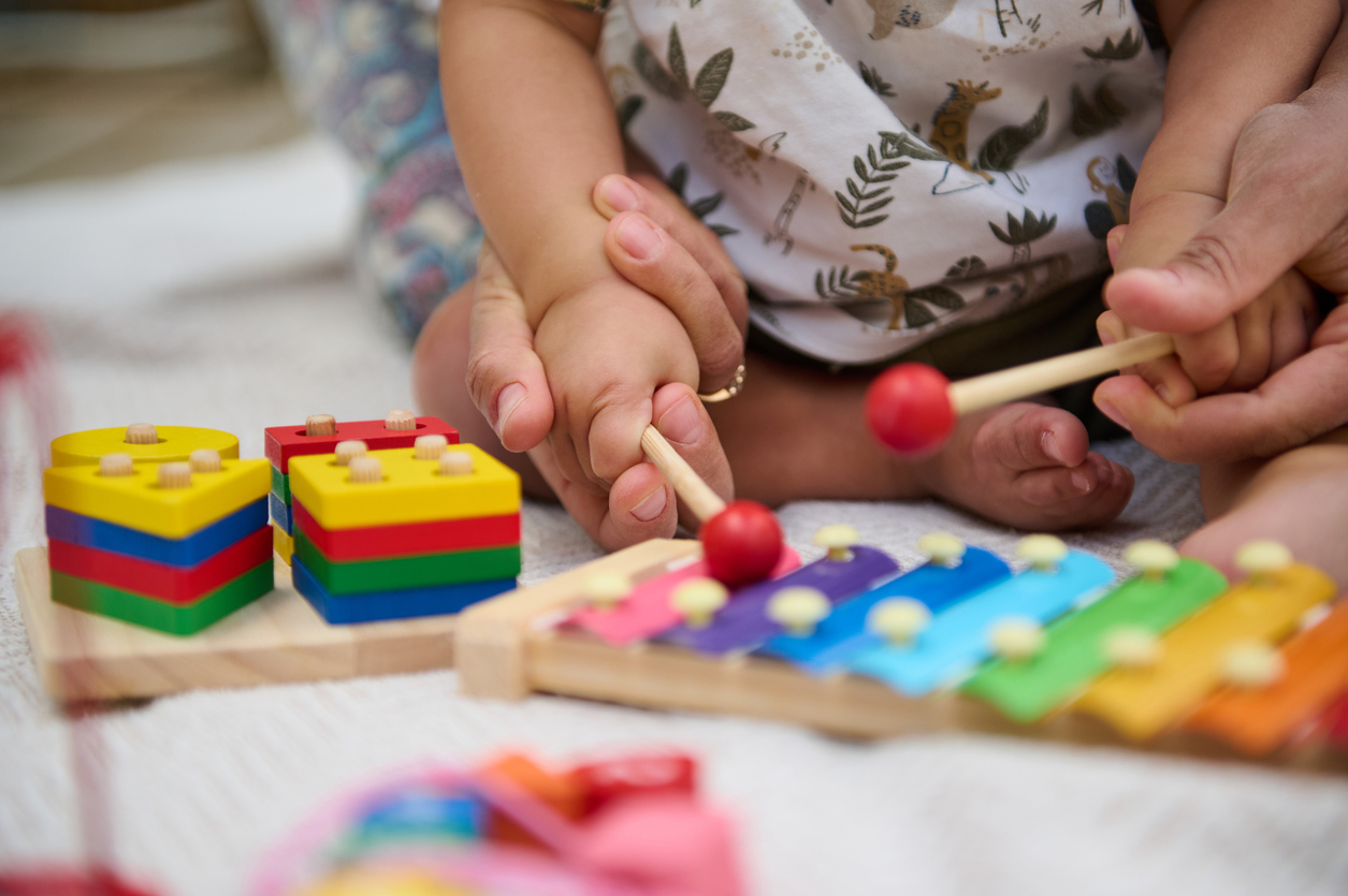 Baby being assisted to play instrument