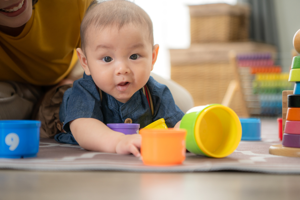 Baby playing on floor with cups
