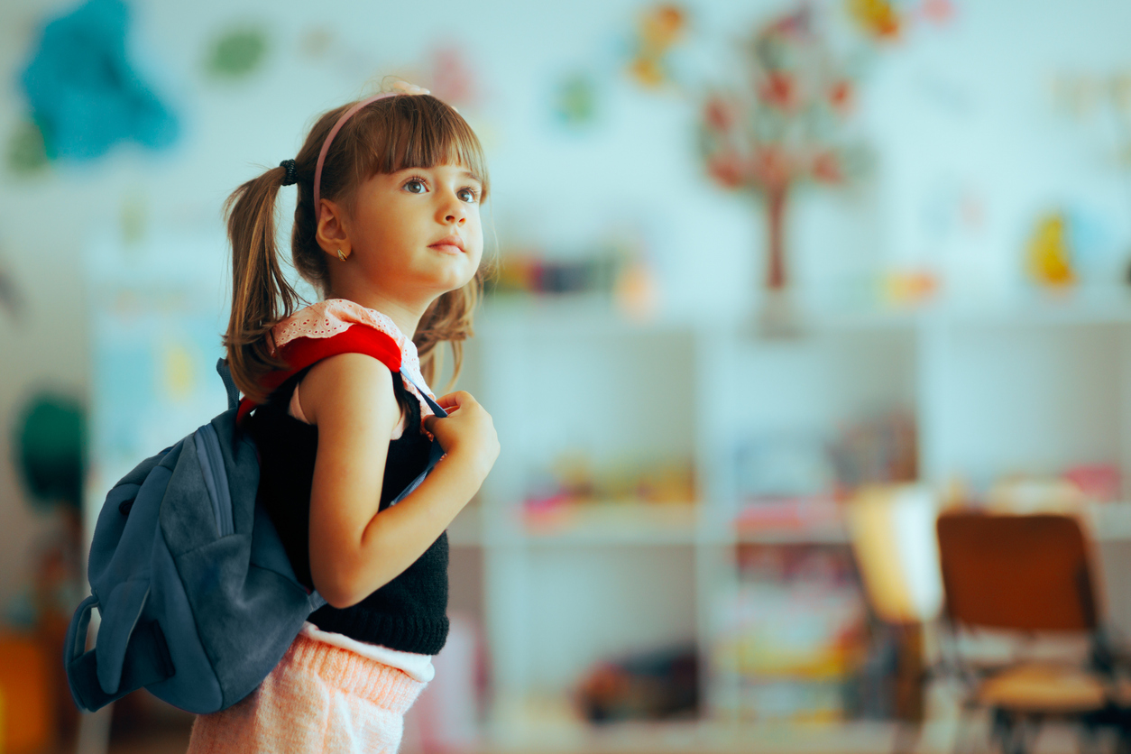 Little girl with backpack in classroom